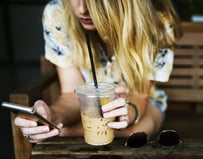 Image of girl on phone with coffee up