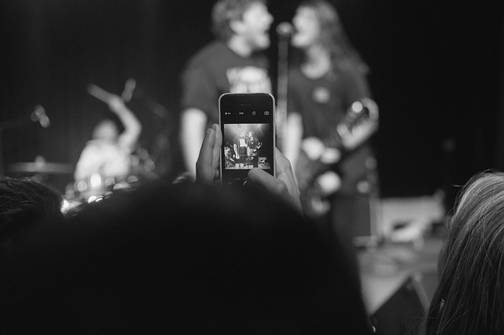 Image of audience member filming concert on smartphone. For successful inbound marketing, it is important to know your audience and they media they use.