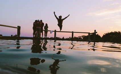 Image of person jumping off dock into water. Social media platforms like Twitter help businesses interact and have fun with customers. 