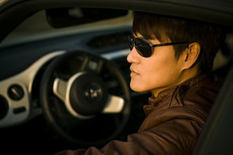 Image of man wearing sunglasses, driving car. Good website design incoporates style and function.
