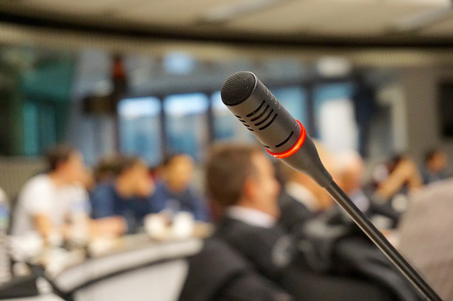 Image of microphone at podium. Public speaking can grow website traffic.