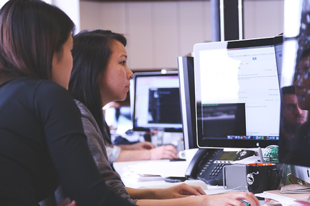 Image of two women analyzing ppc campaign on computer monitors. Digital marketing and inbound tools help make successful PPC campaigns.