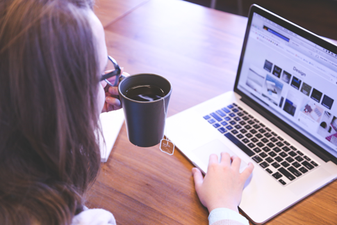 Image of woman at computer reading content on website.