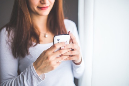 Image of woman using smartphone. Google Adwords and other PPC campaigns should be optimized for mobile.