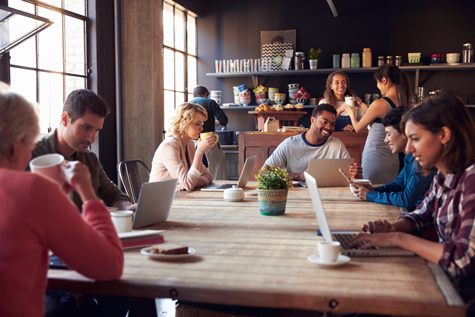 Image of people in coffee shop using computers. Marketing automation expands value and impact or content.