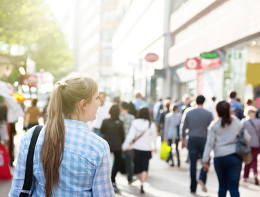 Woman standing in crowd downtown. Use local SEO tactics and inbound marketing tools to attract customers in places like Detroit Michigan.